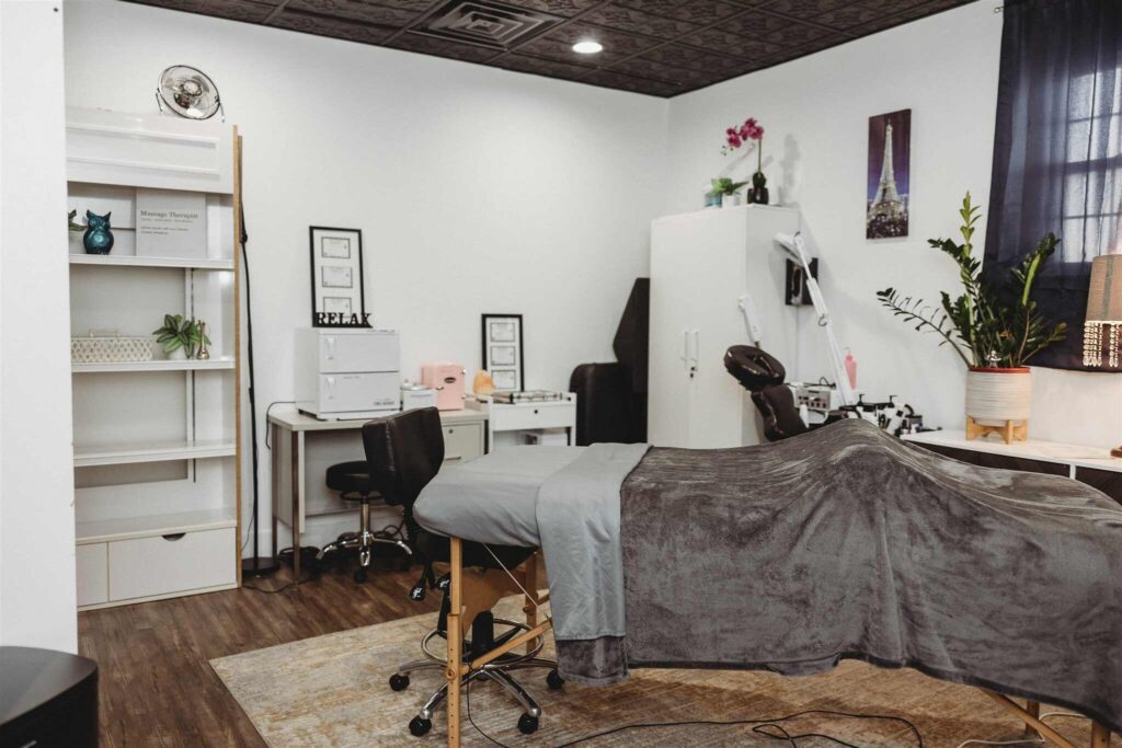 Cozy massage and facial treatment room at New You Health in Peoria, Illinois, featuring a treatment table with plush gray linens, ambient lighting, skincare tools, and a calming spa-like atmosphere.