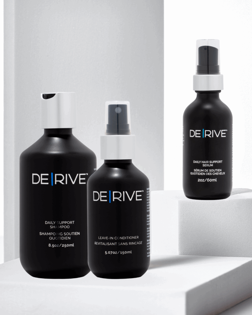 Three DERIVE hair restoration products — Daily Support Shampoo (8.5 oz), Leave-In Conditioner (5.07 oz), and Daily Hair Support Serum (2 oz) — shown on white minimalist blocks with soft lighting, highlighting their sleek black packaging and modern aesthetic.