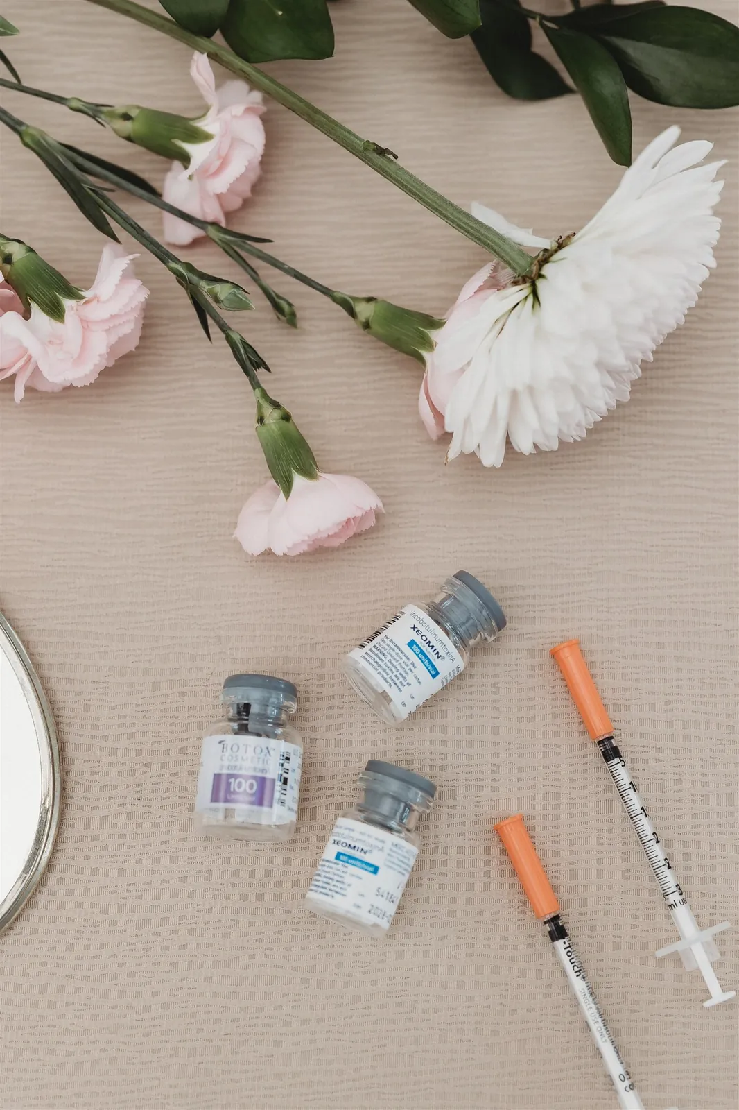 Botox Cosmetic and Xeomin vials with syringes and flowers at New You Health in Peoria, IL